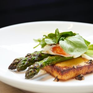 Assiette élégante avec œuf poché et asperges, servie lors d'un dîner spectacle au Royam