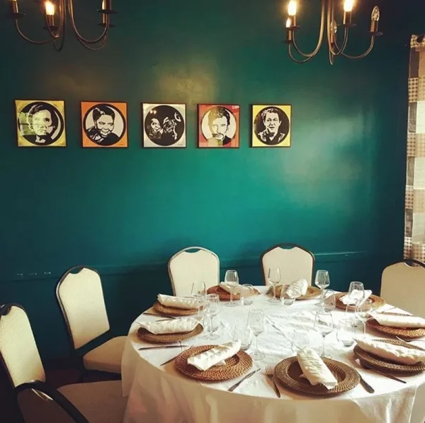 Table dressée dans la salle du Royam, devant un mur vert décoré de portraits d’artistes
